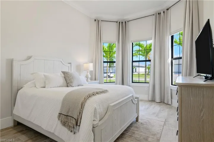 Bedroom with multiple windows, light wood-style flooring, and ornamental molding