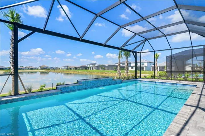 Outdoor pool featuring a water view, a residential view, and glass enclosure