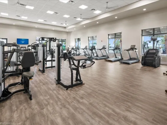 Exercise room with a paneled ceiling, a high ceiling, and wood finished floors