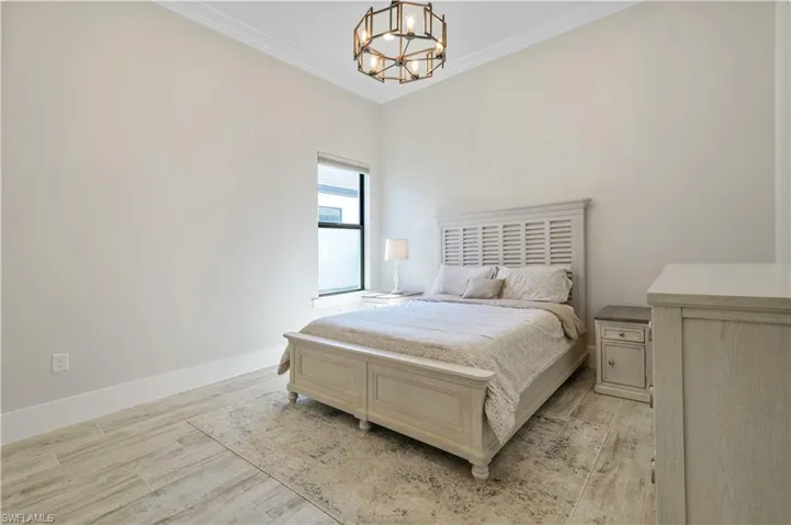 Bedroom with crown molding, a chandelier, and light wood finished floors