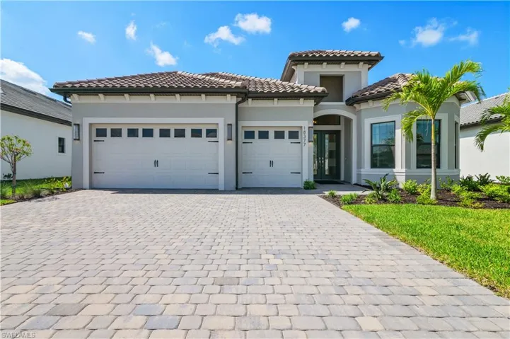 Mediterranean / spanish-style house with an attached garage, decorative driveway, stucco siding, and a tile roof