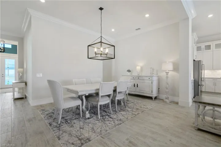 Dining room with a chandelier, crown molding, light wood-type flooring, and recessed lighting