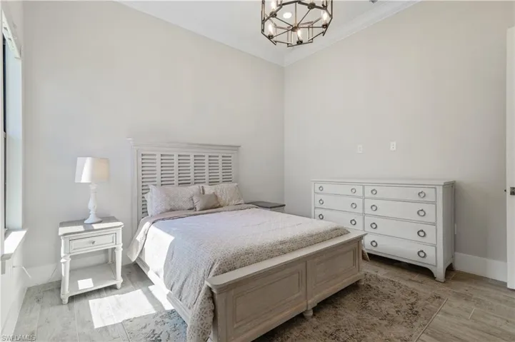 Bedroom with crown molding, a chandelier, and light wood finished floors
