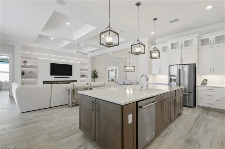 Kitchen with crown molding, appliances with stainless steel finishes, white cabinetry, light countertops, and tasteful backsplash