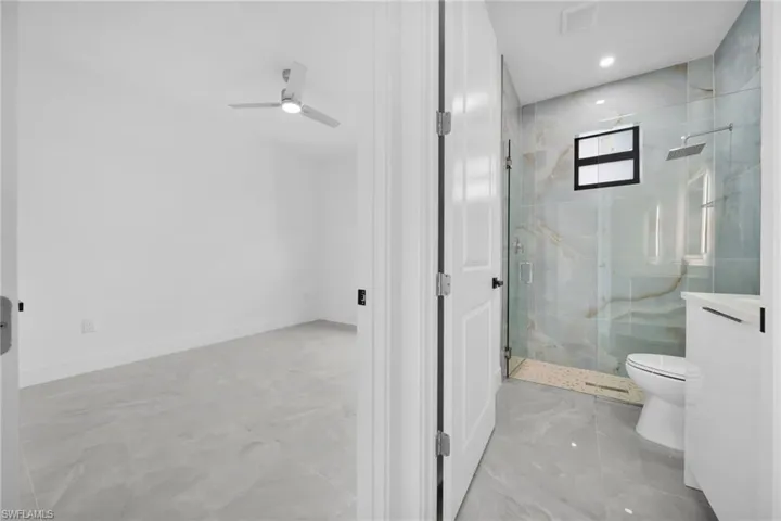 Full bath with a marble finish shower, ceiling fan, light marble finish floors, and recessed lighting