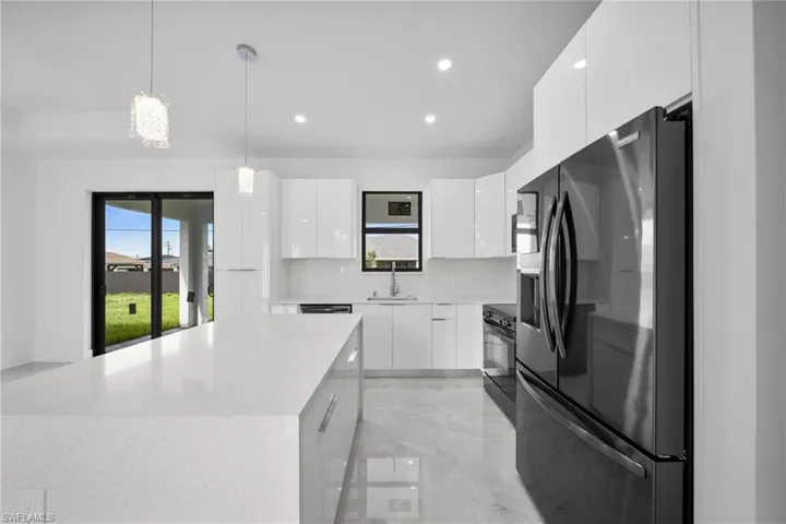 Kitchen with refrigerator with ice dispenser, hanging light fixtures, white cabinetry, modern cabinets, and light marble finish floors