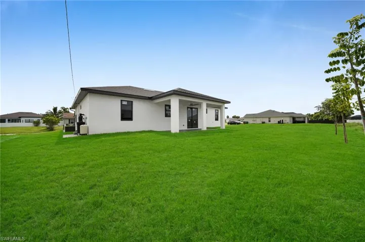 Back of property featuring a yard and stucco siding