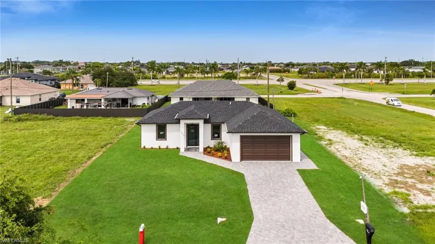 View of front of property featuring decorative driveway, a residential view, a front yard, a garage, and stucco siding