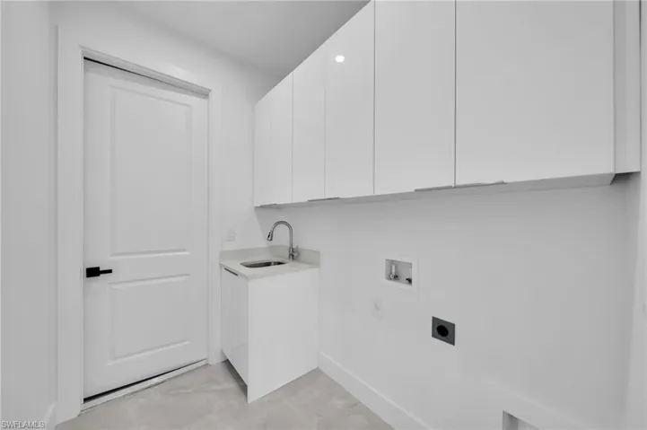 Washroom featuring hookup for an electric dryer, light tile patterned floors, hookup for a washing machine, and cabinet space
