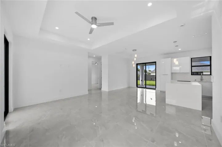 Unfurnished living room with a raised ceiling, recessed lighting, and a ceiling fan