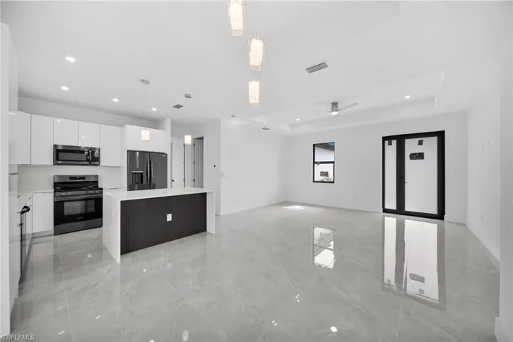 Kitchen featuring pendant lighting, white cabinetry, a center island, black range oven, and a raised ceiling