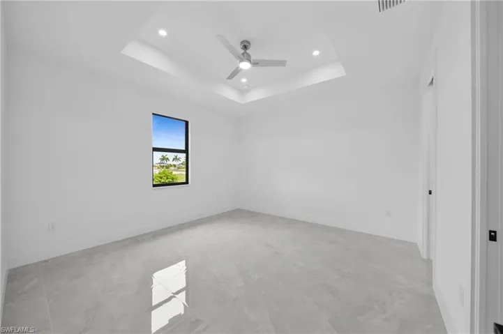 Unfurnished room featuring a raised ceiling, ceiling fan, and recessed lighting
