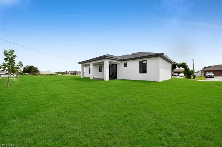 Rear view of property featuring stucco siding and a yard