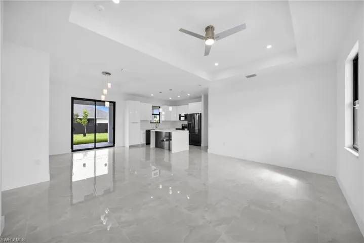 Unfurnished living room featuring a raised ceiling, recessed lighting, and ceiling fan