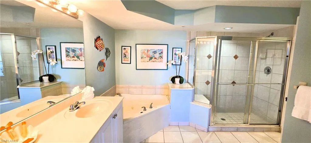 Bathroom featuring a jetted tub, vanity, light tile patterned floors, and a shower stall