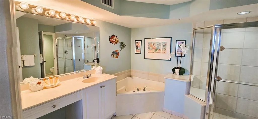 Bathroom featuring vanity, a bath, a shower stall, and light tile patterned floors
