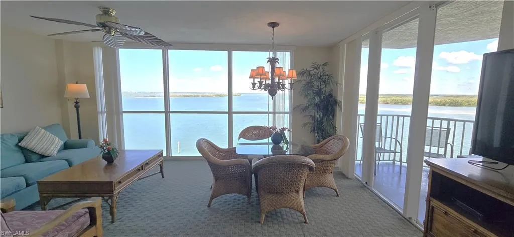 Carpeted dining space featuring expansive windows, a chandelier, and a ceiling fan