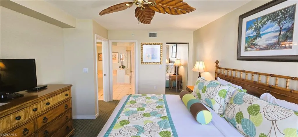 Bedroom with ceiling fan, dark colored carpet, connected bathroom, and a closet