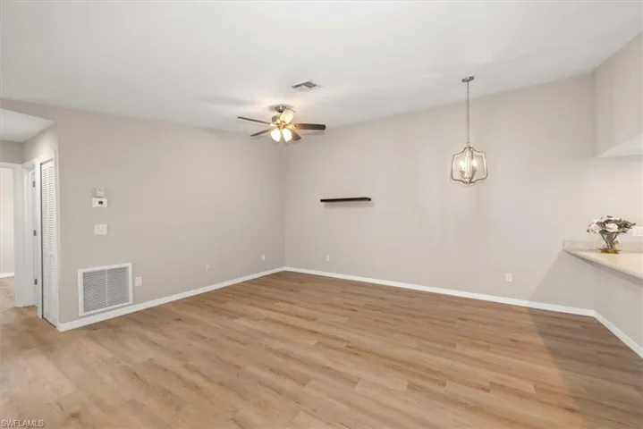 Unfurnished living room with light wood finished floors, ceiling fan, and a chandelier