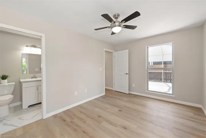 Unfurnished bedroom featuring light wood finished floors, ceiling fan, and ensuite bathroom
