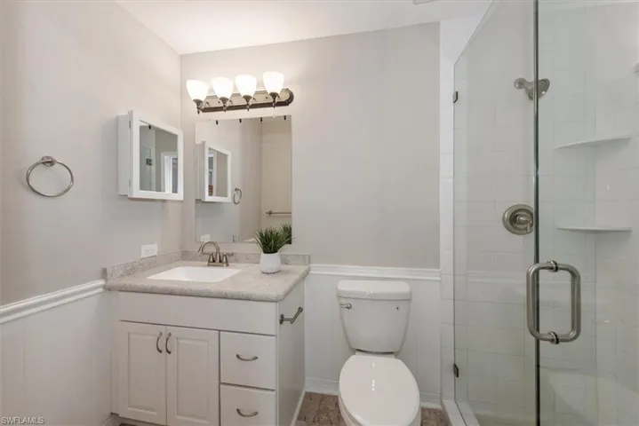 Bathroom with a wainscoted wall, vanity, and a stall shower
