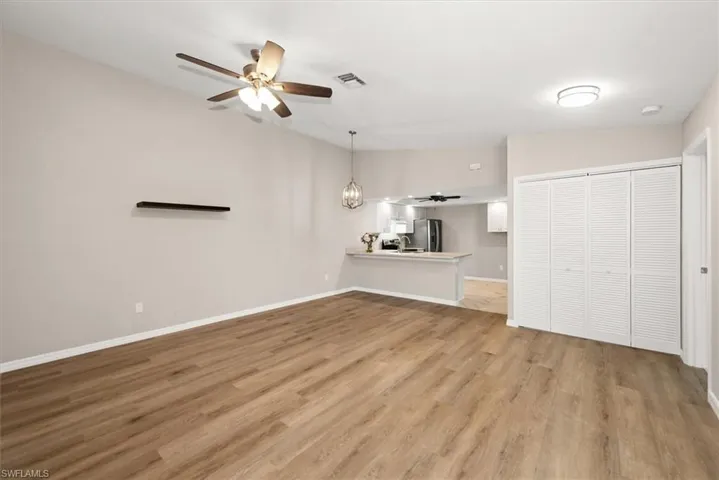 Unfurnished living room featuring ceiling fan, light wood-style flooring, and a chandelier
