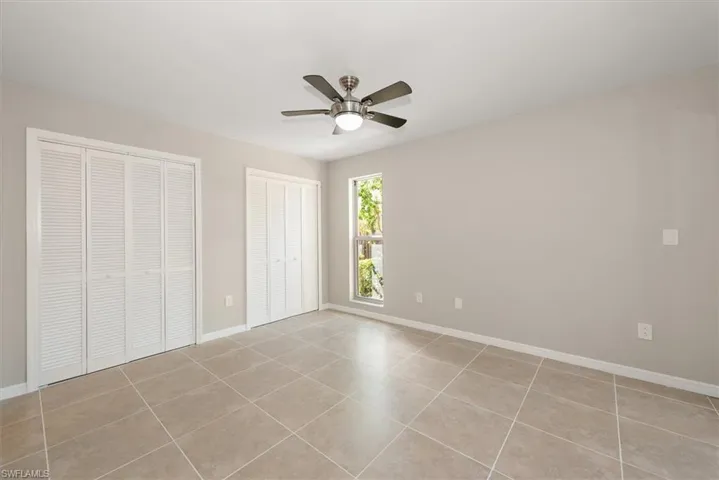 Unfurnished bedroom with multiple closets, light tile patterned floors, and a ceiling fan