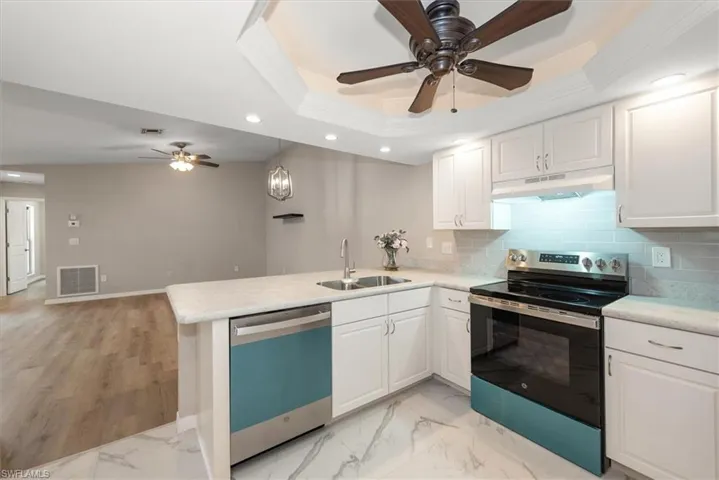 Kitchen with electric range, a tray ceiling, backsplash, recessed lighting, and dishwasher