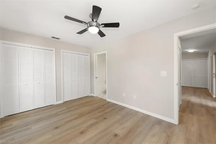 Unfurnished bedroom with two closets, light wood-style floors, a ceiling fan, and connected bathroom