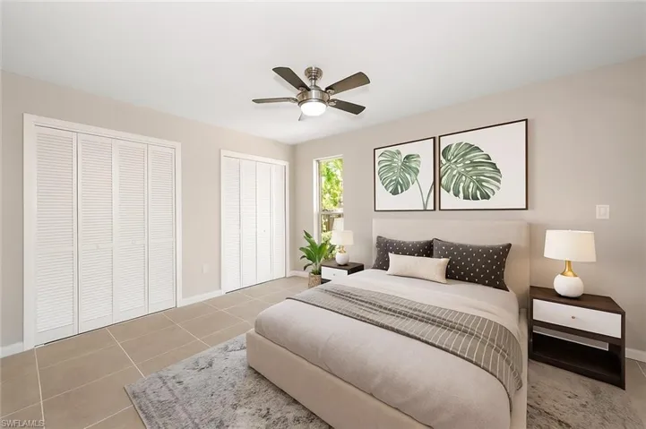 Bedroom with multiple closets, light tile patterned floors, and a ceiling fan