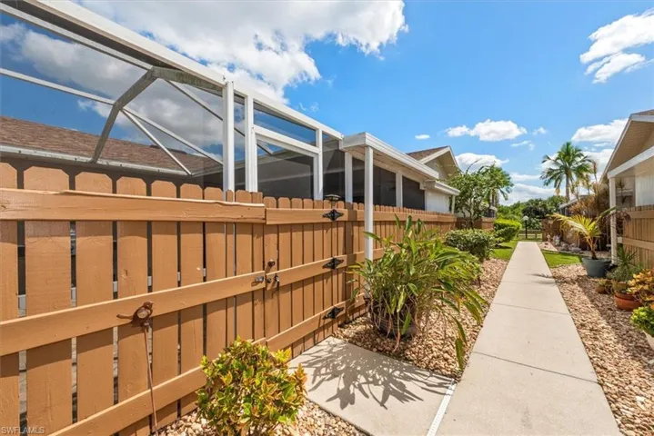 View of side of property featuring a sunroom, a gate, and glass enclosure