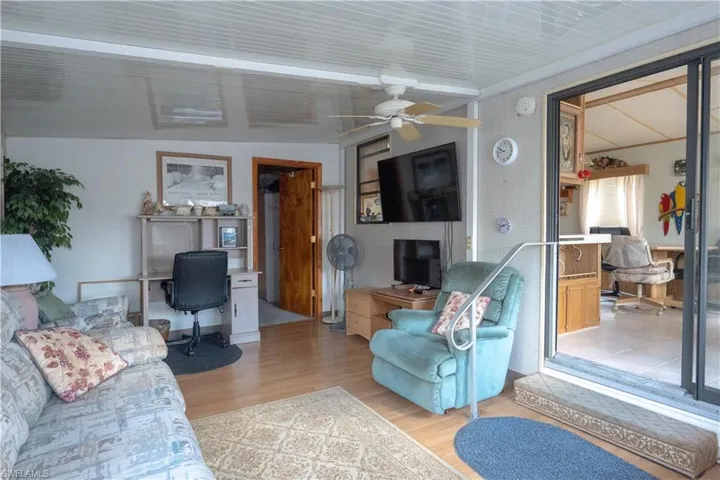 Sunroom featuring wood-finish flooring, a ceiling fan, and sliding glass doors