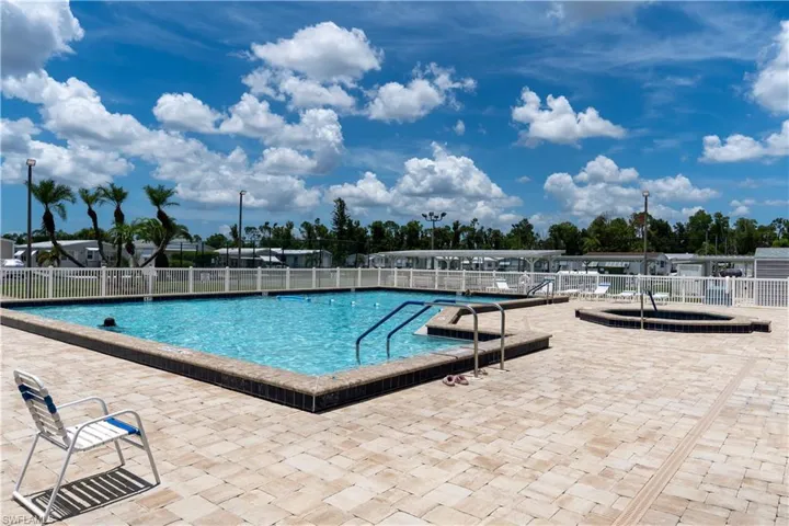Resort-style pool area featuring a rectangular swimming pool, an integrated spa, and extensive paver decking