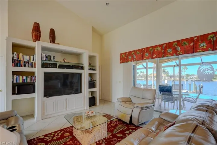 Living area featuring high vaulted ceiling, built in shelves, and light tile patterned floors