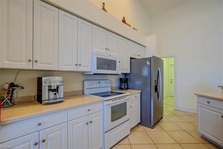 Kitchen featuring white cabinets, light countertops, and white appliances