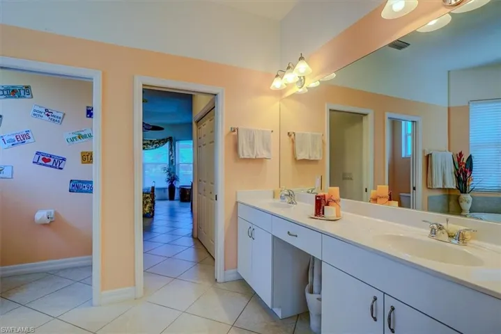Ensuite bathroom featuring tile patterned floors, baseboards, visible vents, and a sink