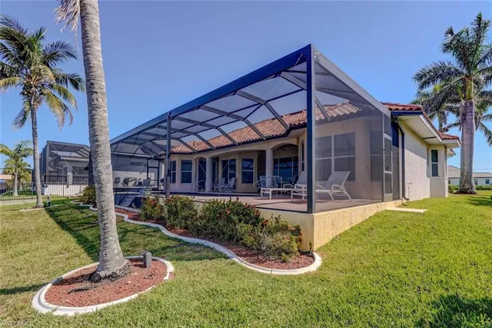 Rear view of property featuring a patio area, a lawn, a tiled roof, and stucco siding