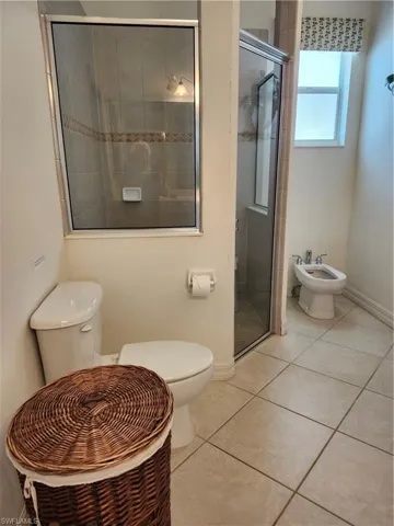 Full bath with baseboards, toilet, a bidet, tile patterned floors, and a stall shower