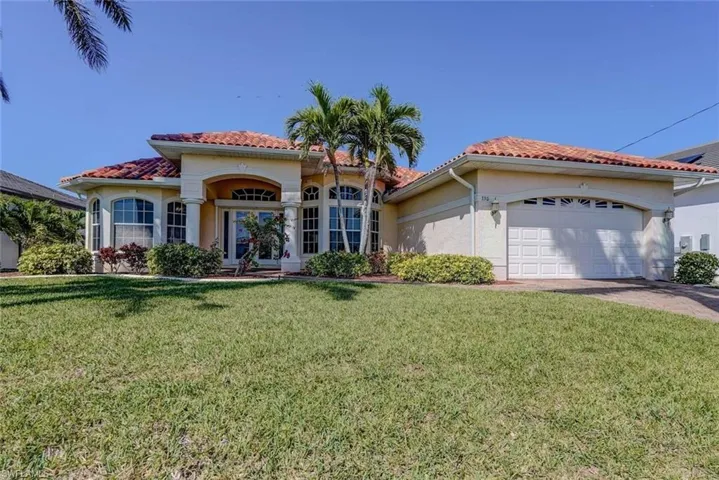 Mediterranean / spanish home featuring an attached garage, a tiled roof, a front yard, and stucco siding
