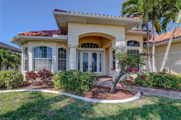 Doorway to property with stucco siding, a tile roof, a yard, and french doors