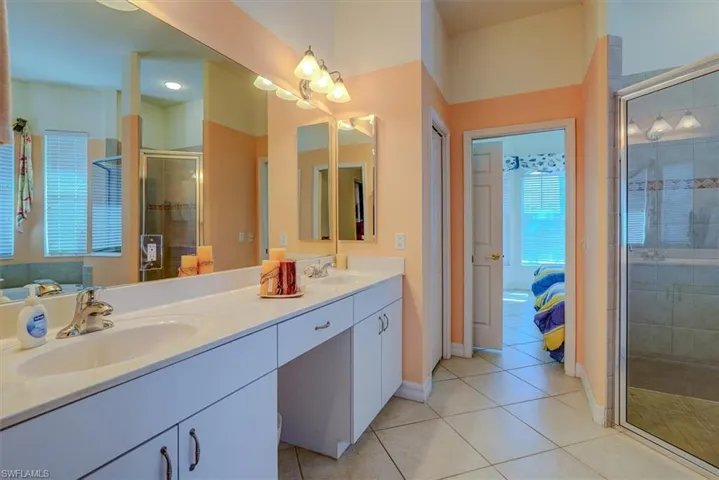 Full bath featuring a shower stall, connected bathroom, tile patterned flooring, and a sink