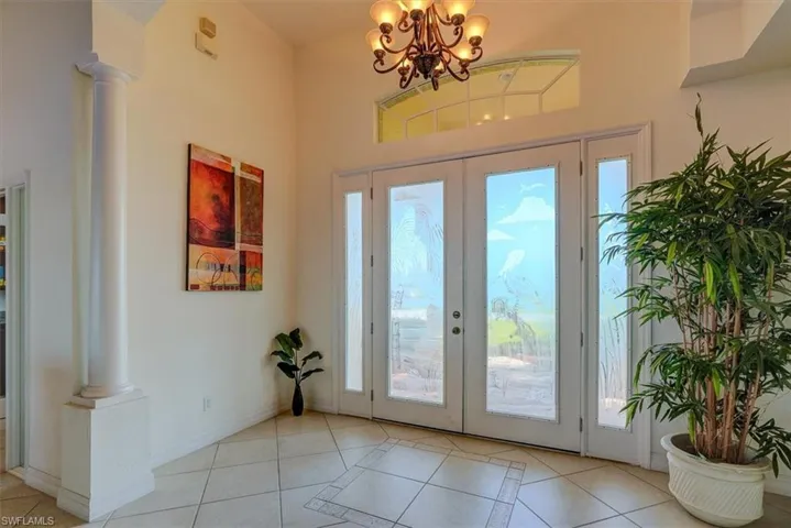 Doorway with a healthy amount of sunlight, light tile patterned floors, and decorative columns