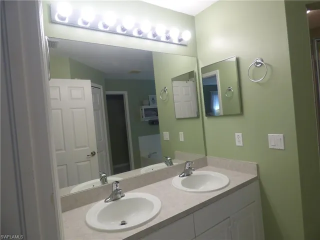 Bathroom with dual sinks and vanity with extensive cabinet space