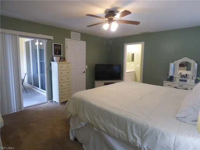 Bedroom featuring carpet, ensuite bath, ceiling fan, and access to exterior