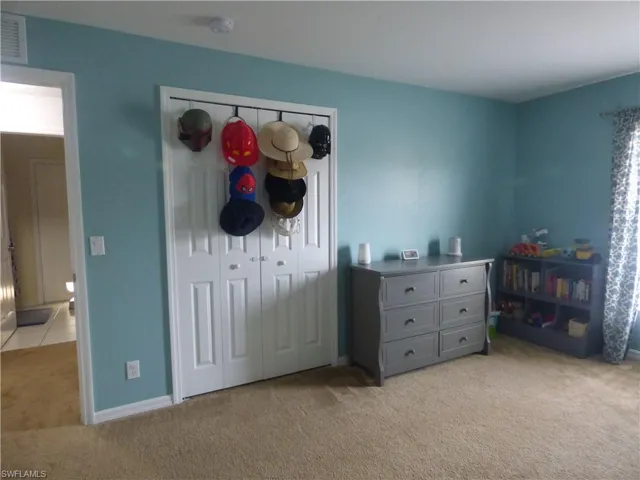 Bedroom with light colored carpet and a closet