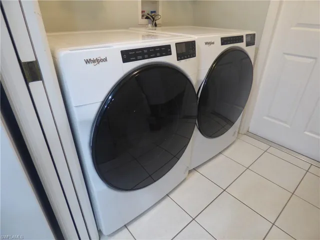 Washroom with brand new washer and dryer, light tile floors, and washer hookup