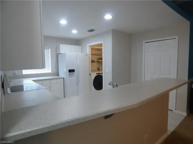 Large Kitchen featuring brand new refrigerator with ice dispenser, white cabinets, range, and light tile floors