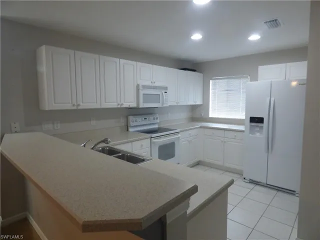 Large Kitchen featuring white appliances, sink, white cabinetry, and kitchen peninsula