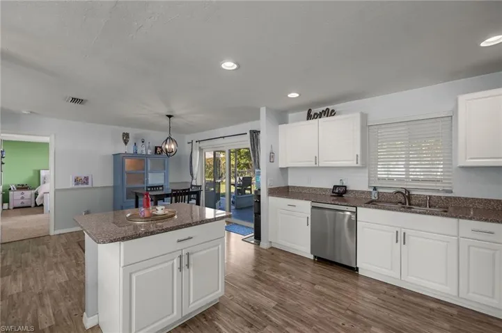 Kitchen with decorative light fixtures, white cabinetry, sink, dark hardwood / wood-style flooring, and stainless steel dishwasher