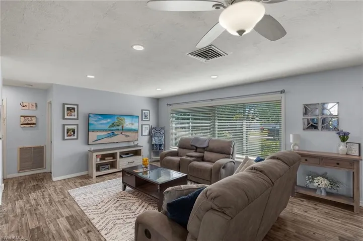 Living room featuring hardwood / wood-style flooring, ceiling fan, and a textured ceiling